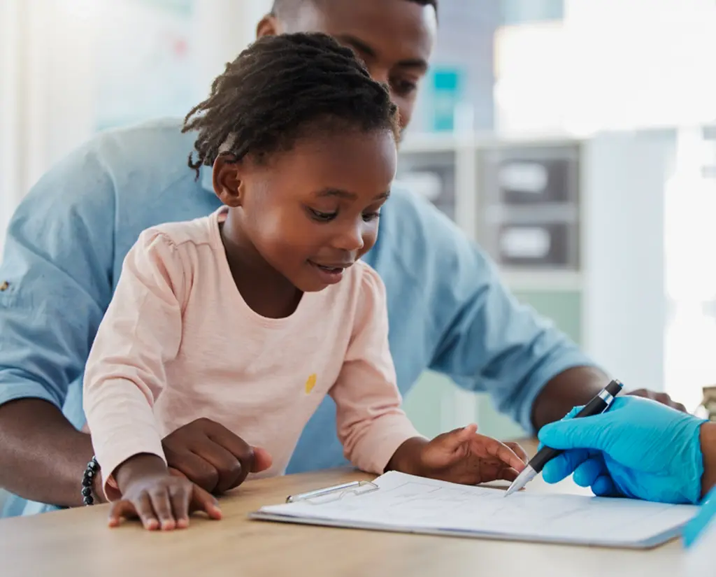 SHA vs Private Medical Insurance in Kenya: What's the Difference? 1 Father and young daughter completing a medical cover application form with a healthcare provider.